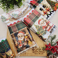 Panos de prato de Natal em sacaria de algodão com barrado xadrez, estampas de Papai Noel, quebra-nozes e crianças, embalados como presente com tag de Feliz Natal
